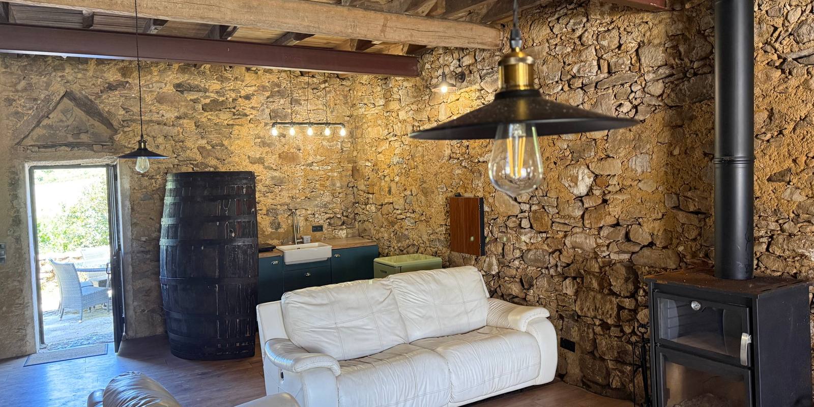 The adega: stone walls, a big wine barrel, white leather sofas and a wood stove